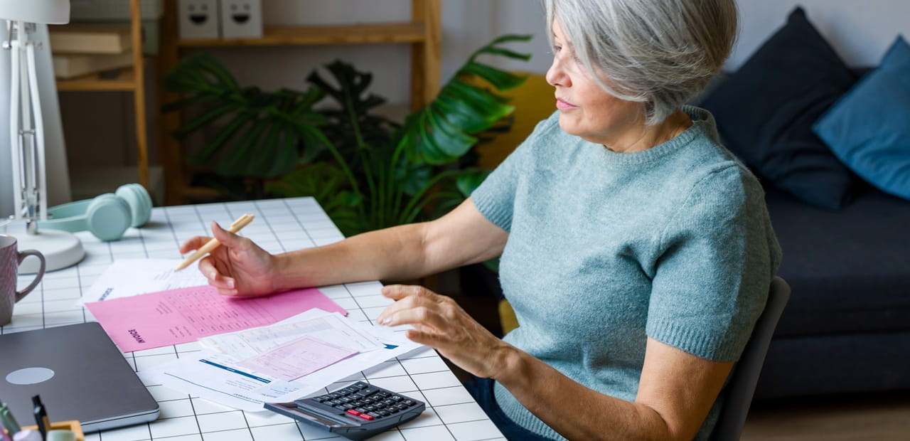 A retired woman reviewing her personal finances to align debt management with wealth-building goals.