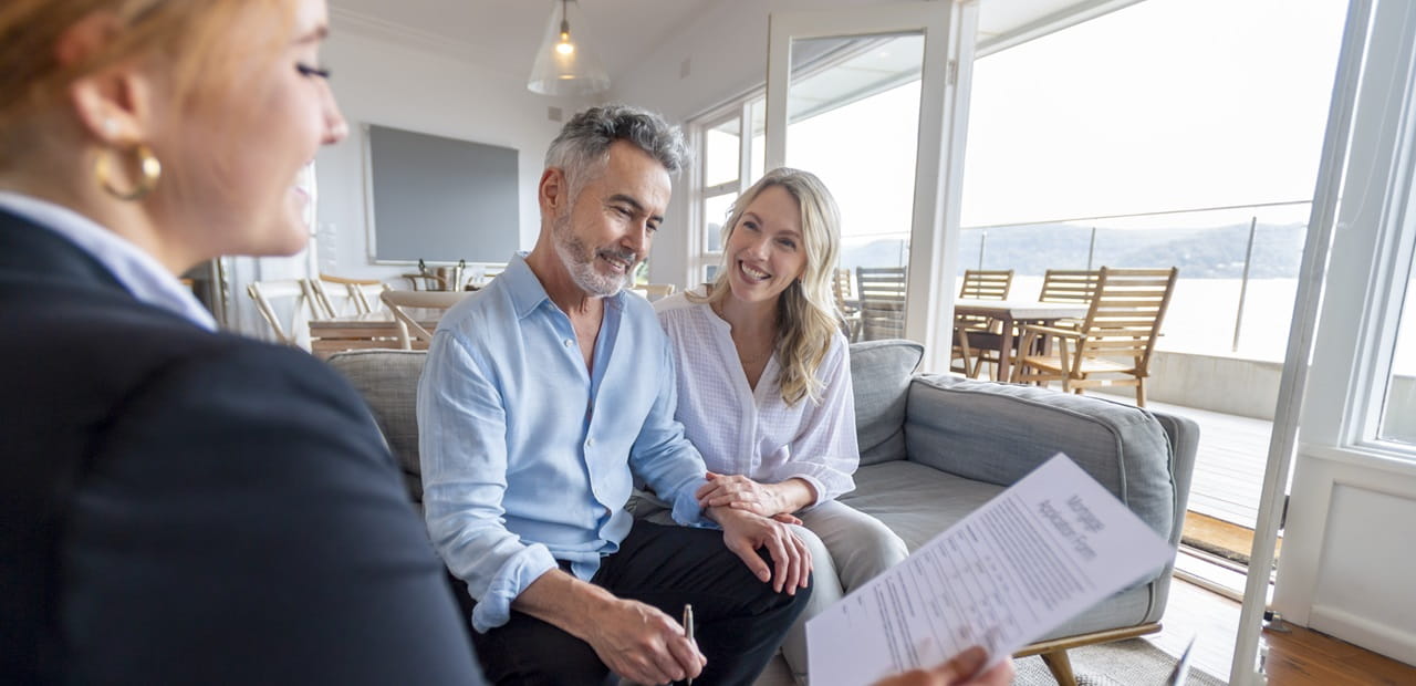 Happy mature couple meeting financial advisor seated in their home